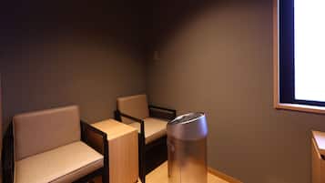 Ein Zimmer mit zwei Stühlen, einem kleinen Tisch und einem Mülleimer.