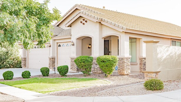 Ein eingeschossiges Haus mit einer beige farbenen Fassade, Steinverzierungen und einem Ziegeldach.