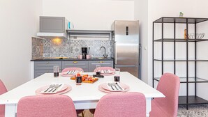 Una cocina moderna con una mesa de comedor para cuatro personas, con sillas y platos rosas.