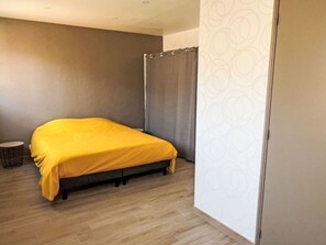Et værelse med en seng, et lille bord og et gardin.