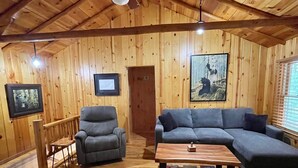 A wooden interior with a sofa, armchairs, and a coffee table. - Beautiful 2 BR Lakefront Cabin on Long Lake, Harrison Mi (Harrison)