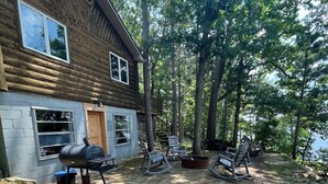 A cabin with a deck, outdoor seating, and a grill area. - Beautiful 2 BR Lakefront Cabin on Long Lake, Harrison Mi (Harrison)