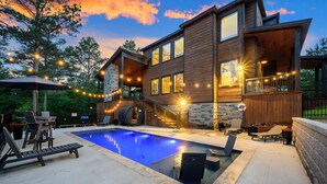 A modern house with a swimming pool, outdoor seating, and string lights.