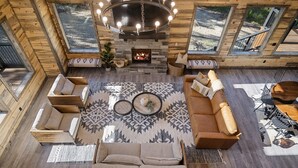 A cozy cabin interior with a fireplace, wooden walls, and a seating area with a sofa and chairs.