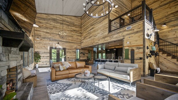 A spacious living area with a fireplace, leather sofas, and a large rug.