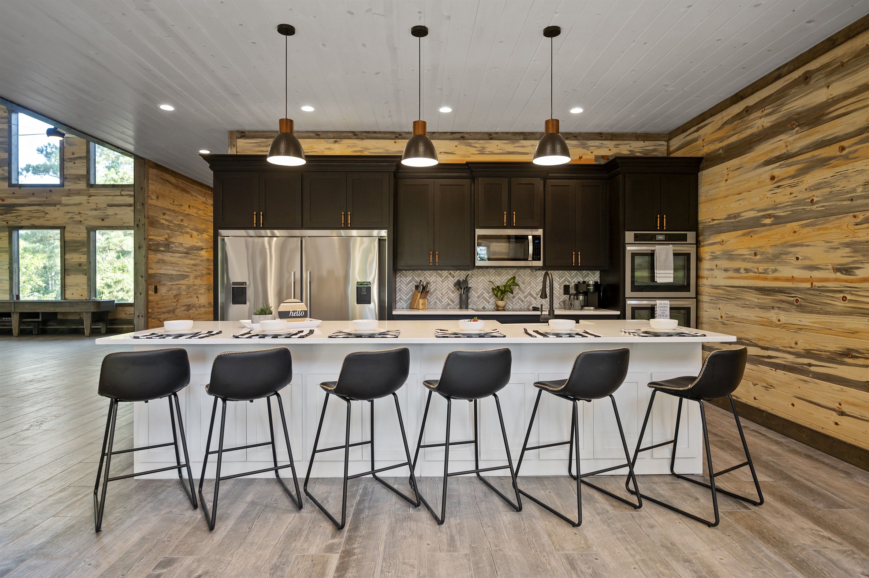 Una cocina moderna con armarios oscuros, electrodomésticos de acero inoxidable y una isla central con taburetes de bar.