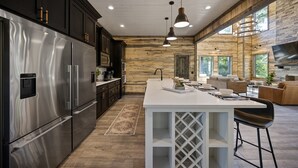 A modern kitchen with a large island, stainless steel appliances, and a stone accent wall.
