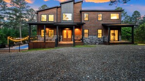 A two-story house with a covered porch, a swimming pool, and a gravel driveway.