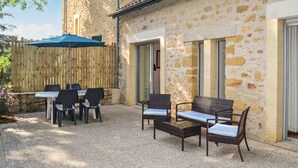 Eine Terrasse im Freien mit Tisch und Stühlen, einem Holzzaun und einem Gebäude mit Ziegeldach.