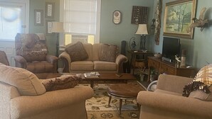 A living room with a sofa set, a coffee table, a television, and decorative items on the walls.