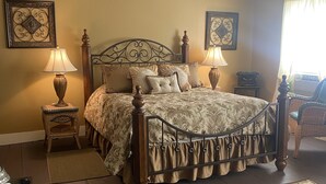 A bedroom with a wooden four-poster bed, two bedside lamps, a rug, and a small table with a lamp.
