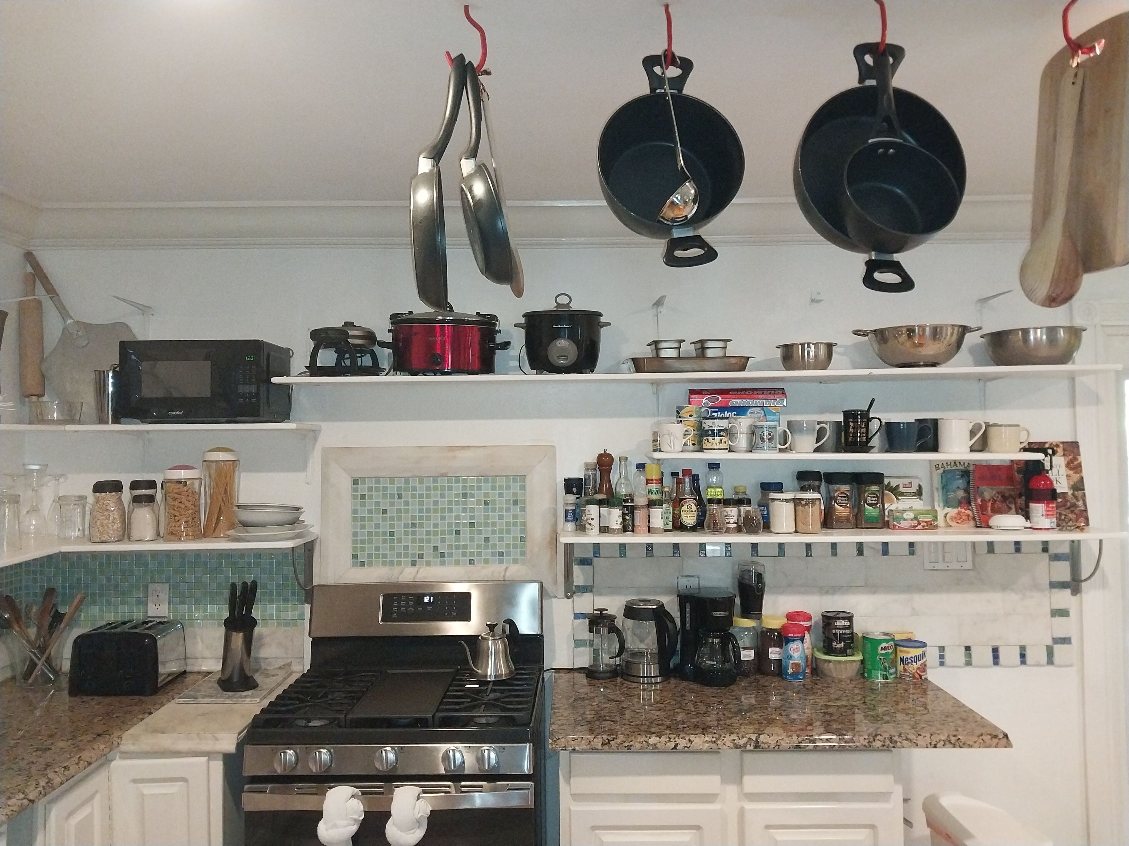 A kitchen with a stove, microwave, and various utensils and appliances.