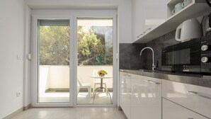 Eine moderne Küche mit einer Schiebeglasdoor zum Balkon, einer Mikrowelle und einem Spülbecken.