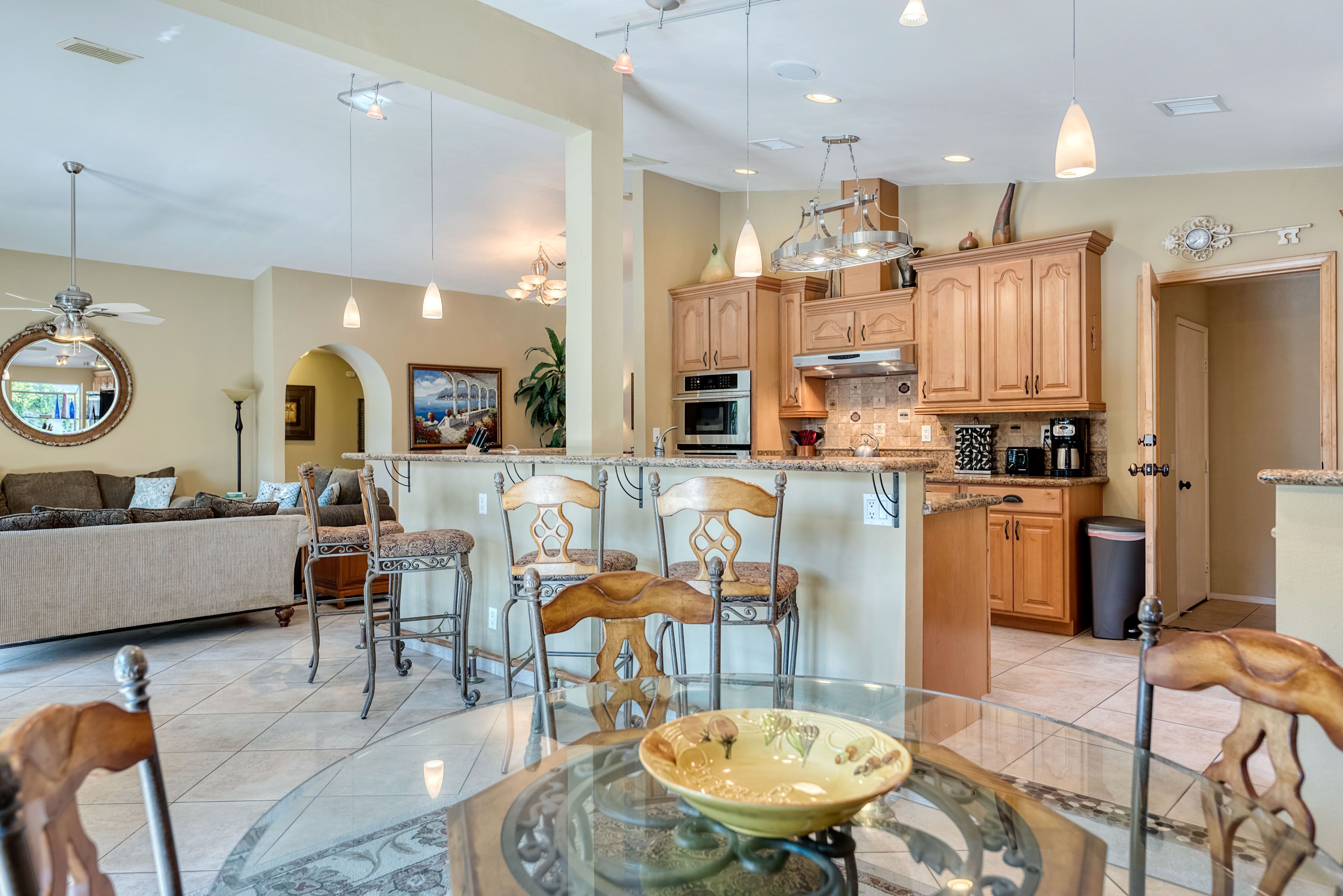 A spacious living area with a glass dining table, wooden chairs, and a sofa. - Private Oasis Overlooking Golf Course  (Palm Desert)