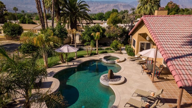 A swimming pool with a circular design, surrounded by palm trees and a patio area with lounge chairs and umbrellas. - Private Oasis Overlooking Golf Course  (Palm Desert)