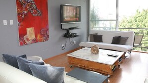 Una sala de estar moderna con un sofá blanco, una mesa de centro y un televisor sobre un mueble.