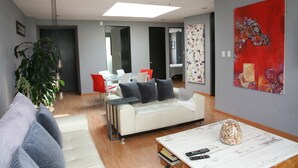 Una sala moderna con un sofá blanco, una mesa de centro y un comedor con sillas rojas.
