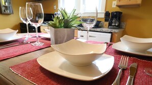 A dining table set with white plates, bowls, and silverware. A potted plant is placed on the table, and there are wine glasses in the background. - ★ Downtown Princeton Elegance ★ (Princeton)