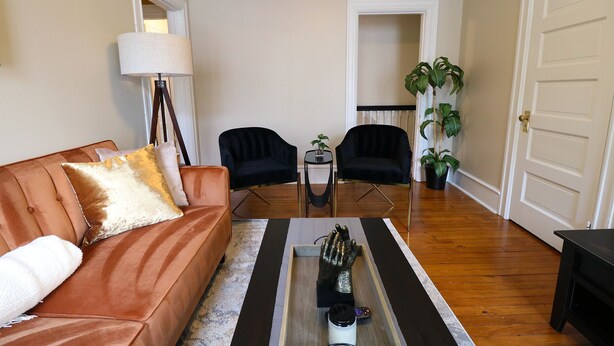 A living room with a brown sofa, two black chairs, a small table with a lamp, and a potted plant. - ★ Downtown Princeton Elegance ★ (Princeton)