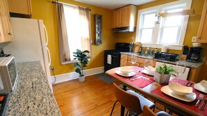 A kitchen with wooden cabinets, a granite countertop, a dining table set with plates and glasses, and a potted plant. - ★ Downtown Princeton Elegance ★ (Princeton)