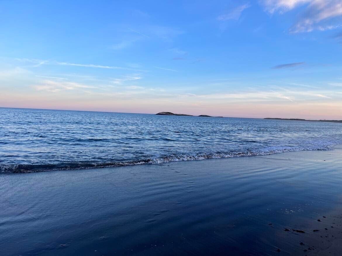 A beach with calm water and a clear sky.