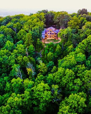 Ein großes, zweistöckiges Holzhaus, umgeben von dichtem Wald.