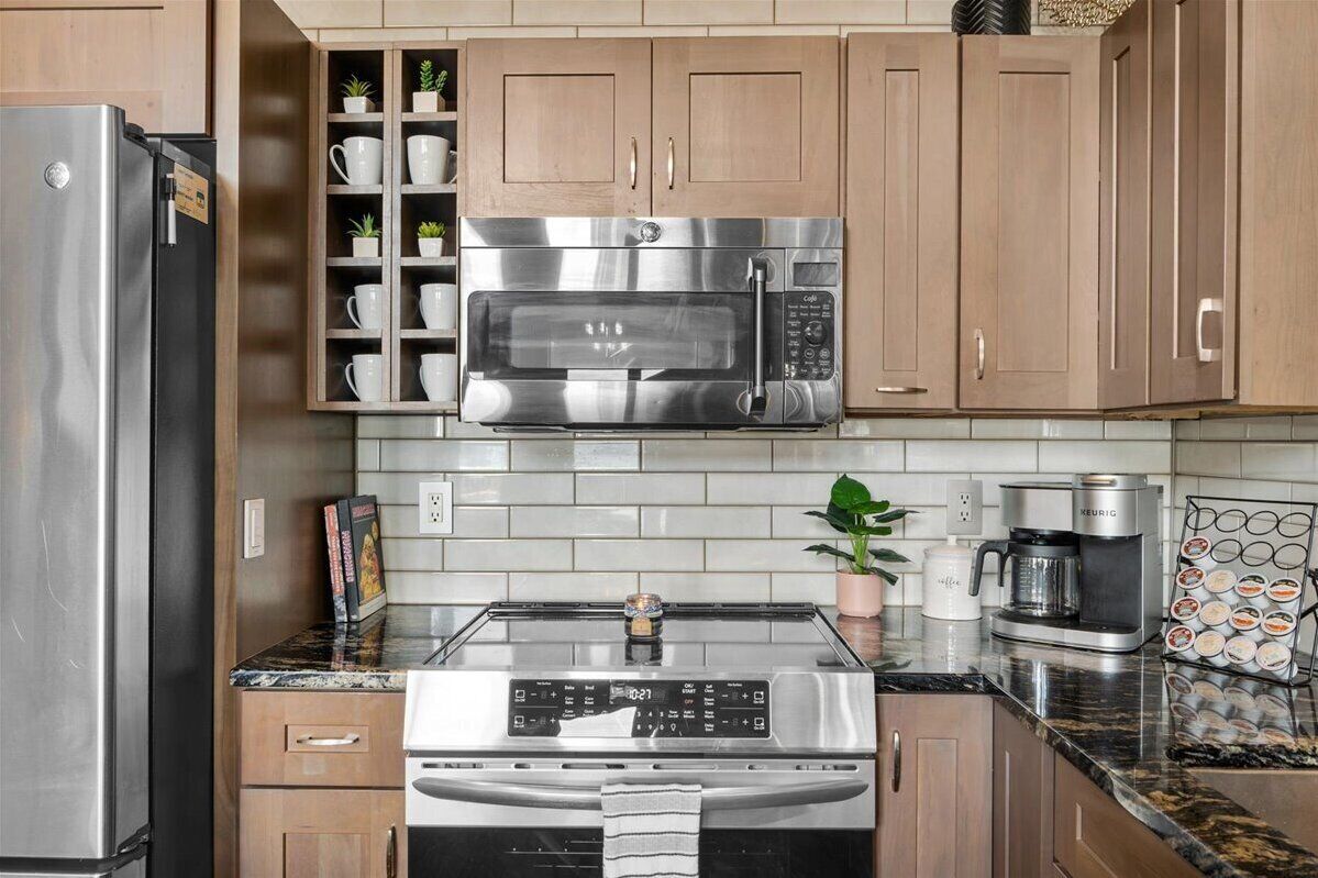 A modern kitchen with stainless steel appliances, wooden cabinets, and a coffee maker.