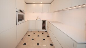 A compact kitchen with white cabinets, a built-in oven, a sink, and a ventilation hood. - Luxury Duplex in the Heart of Cannes (Cannes)