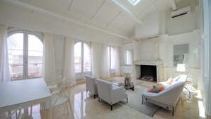 A spacious living room with a glass coffee table, two armchairs, a fireplace, and large windows. - Luxury Duplex in the Heart of Cannes (Cannes)