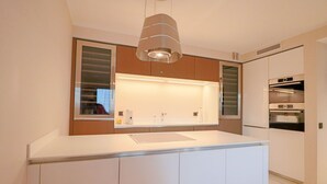A modern kitchen with a central island, built-in oven, and pendant lighting.