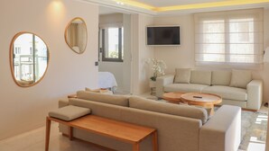 A modern living room with a sofa, a wooden coffee table, and a TV mounted on the wall.