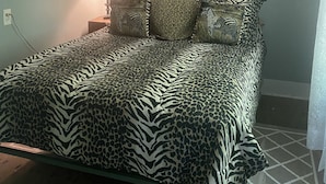 Ein Schlafzimmer mit einem zebra-gemusterten Bettbezug, einem gerahmten Bild eines Löwen und einer Lampe auf dem Nachttisch.