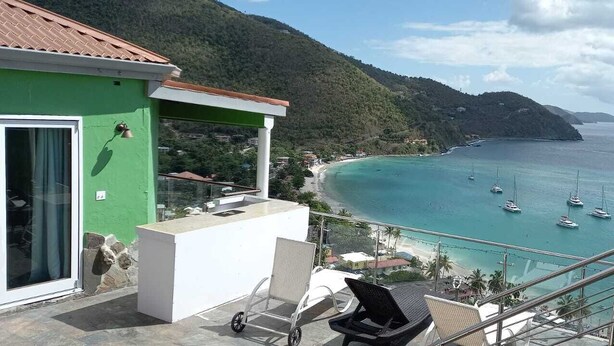 Un balcon offrant une vue sur une mer turquoise, des bateaux et un paysage montagneux.