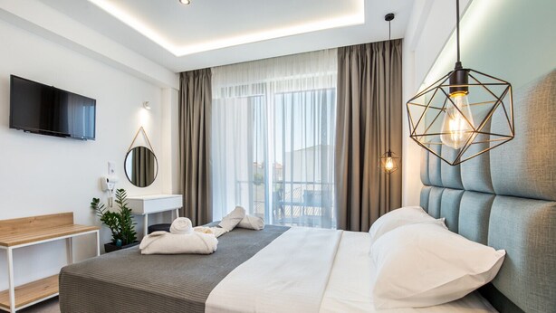 Une chambre d’hôtel moderne avec un grand lit, une table de chevet, une télévision et une vue sur l’extérieur.