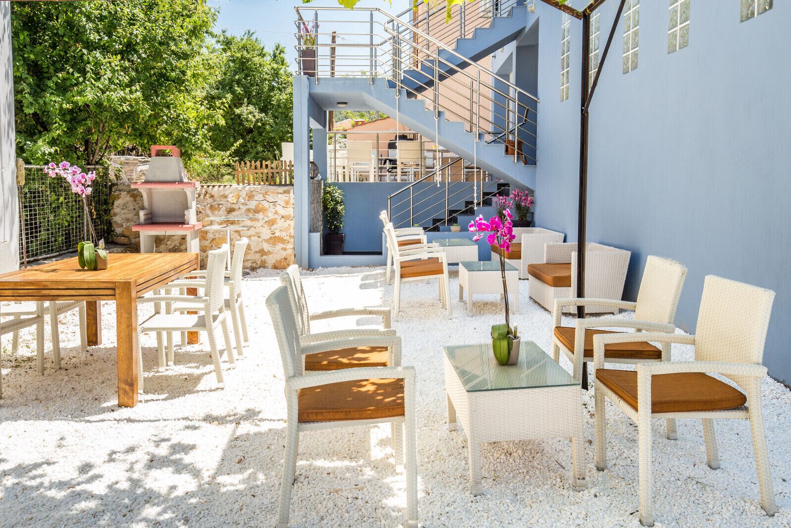 Un espace extérieur aménagé avec des meubles en osier, un mur en pierre et un escalier menant à un niveau supérieur.