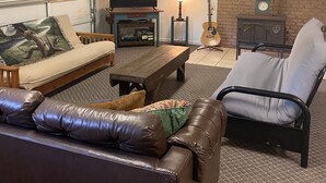 A cozy living room with a sofa, a chair, a coffee table, a fireplace, and a guitar. - CURRENTLY UNDER REPAIR (Deersville)