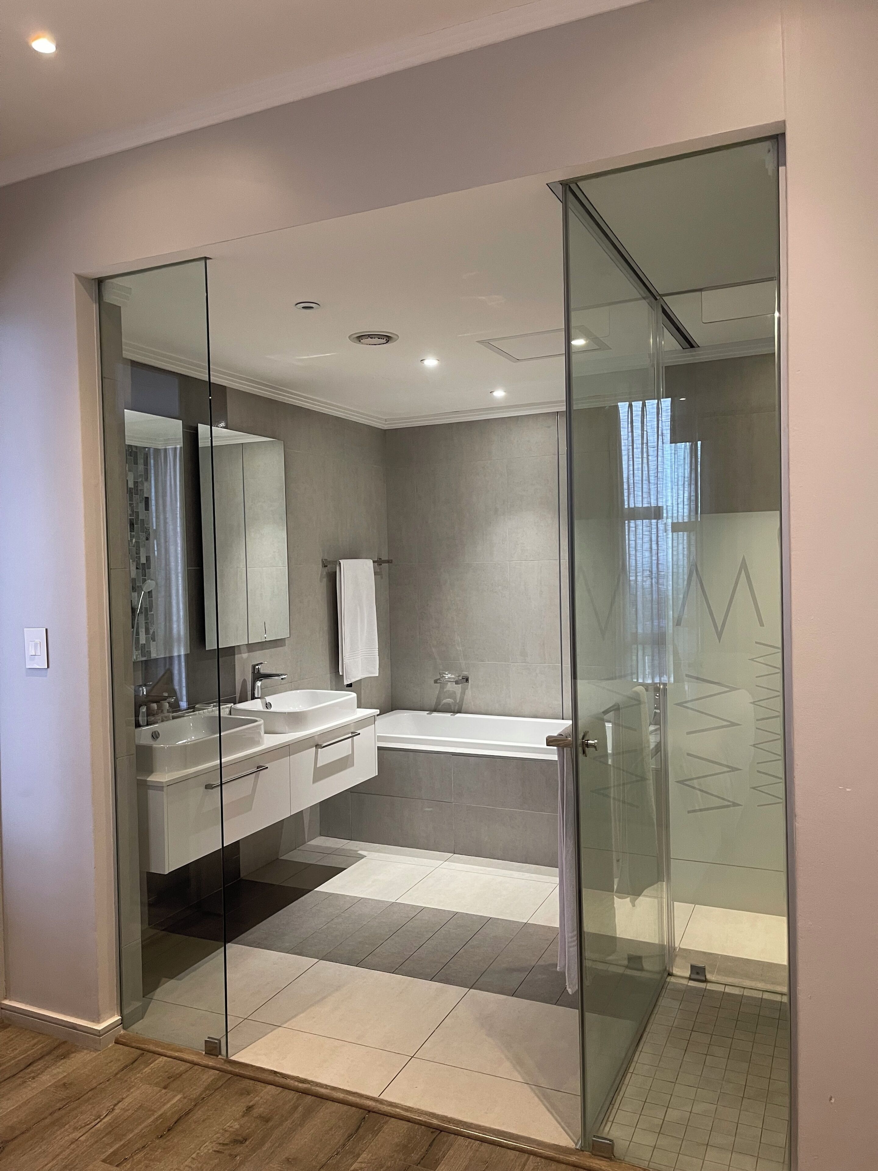A modern bathroom with a glass-enclosed shower, a double sink vanity, and a large mirror.