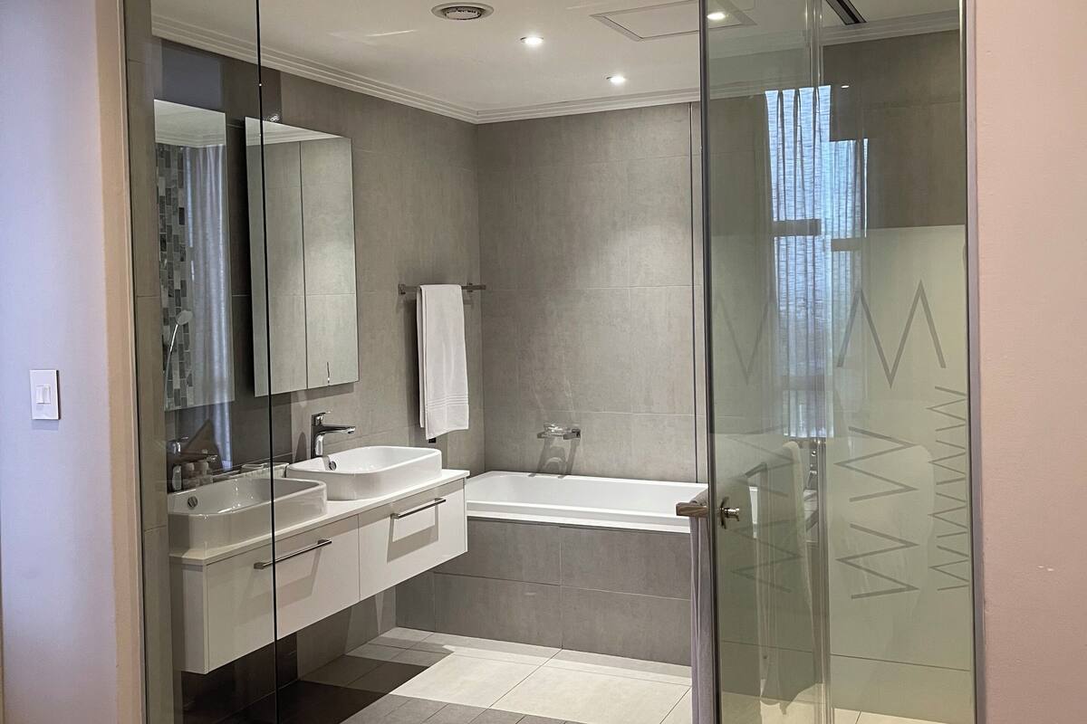 A modern bathroom with a glass-enclosed shower, a double sink vanity, and a large mirror.