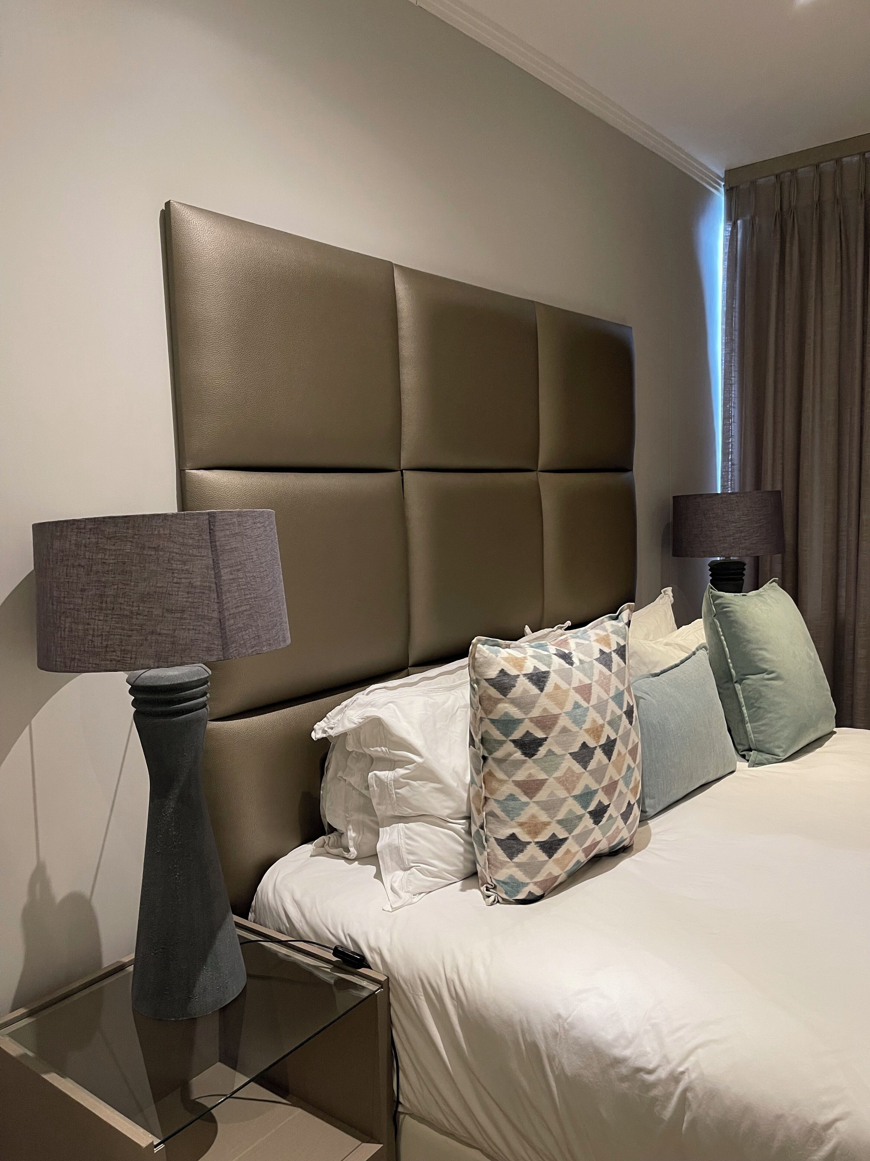 A hotel room with a large bed, two bedside tables, and a headboard.