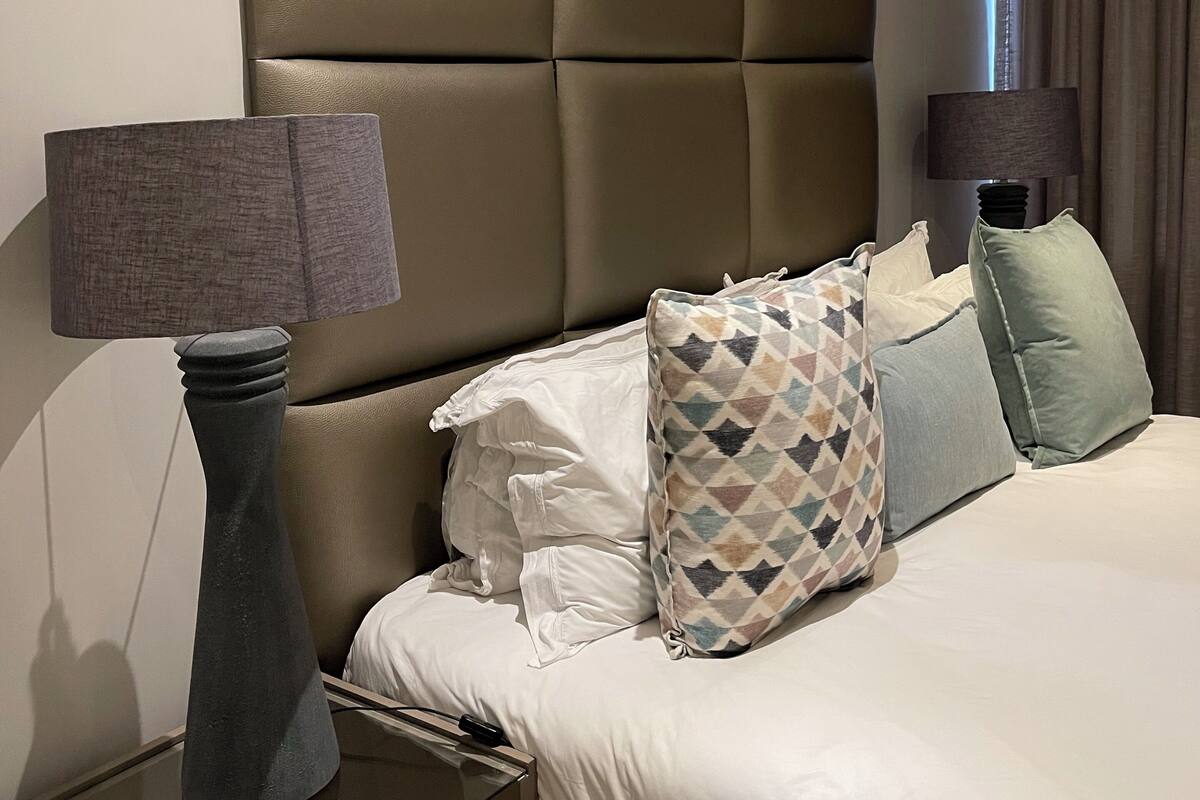 A hotel room with a large bed, two bedside tables, and a headboard.