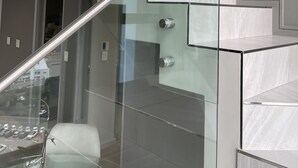 A modern staircase with glass railings and metal handrails, leading to an upper floor. - CGRSA Apartment Sandton (Sandton)