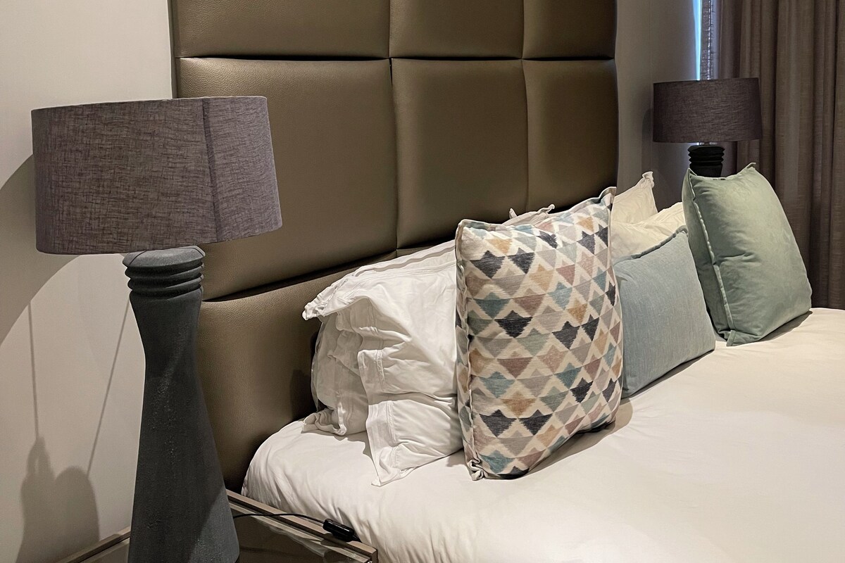 Une chambre d’hôtel avec un grand lit, deux tables de chevet et une tête de lit.
