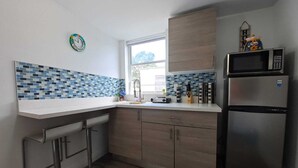 Una cucina moderna con un piano di lavoro bianco, un frigorifero in acciaio inossidabile e un forno a microonde.