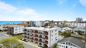 A multi-story residential building with balconies, located near a coastline. - Hidden Gem Oceanview! 3BD/2BR, Steps to the beach! (Ocean City)