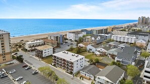 A coastal residential area with a mix of single-family homes and apartment buildings, a parking lot, and a beach in the background. - Hidden Gem Oceanview! 3BD/2BR, Steps to the beach! (Ocean City)