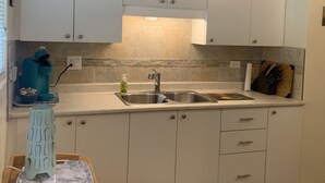 A kitchen with white cabinets, a sink, a countertop, and a coffee maker. - Relaxing - Two Bedroom Suite in Red Deer (Red Deer)