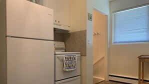 A compact kitchen with a refrigerator, stove, and oven. - Relaxing - Two Bedroom Suite in Red Deer (Red Deer)