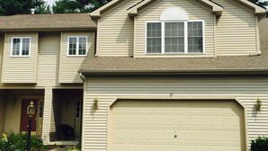 Una casa a due piani con un garage, un'entrata e un piccolo portico.