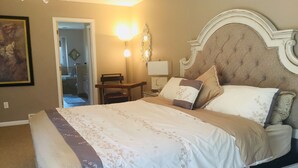 Una camera da letto con un letto grande, un comodino in legno, una sedia e una lampada a parete.