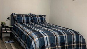 Een slaapkamer met een bed, nachtkastje, lamp en een afbeelding van de Eiffeltoren aan de muur.